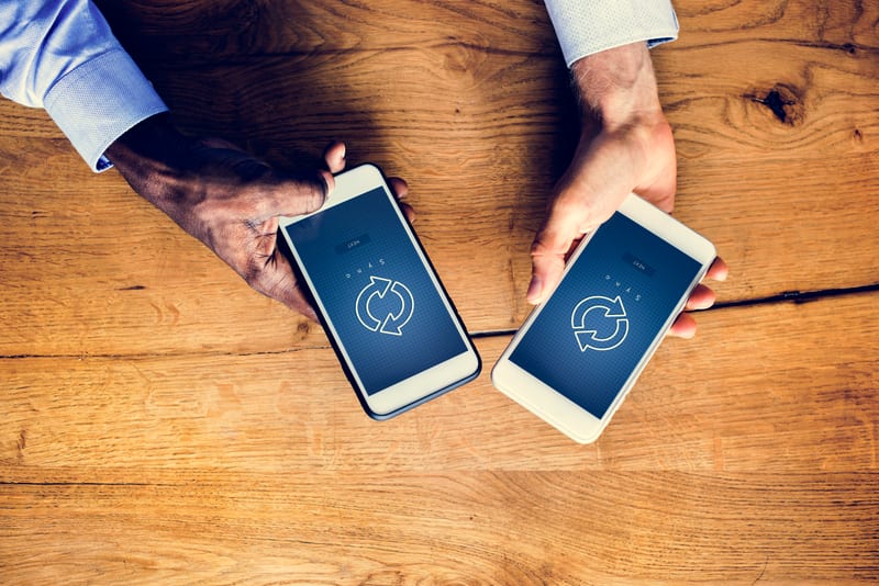 Mains tenant un smartphone avec symbole de synchronisation